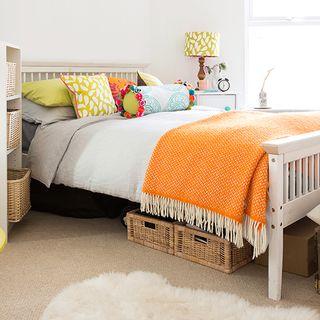 bedroom with orange throw and cushions on bed with cosy carpet on floor