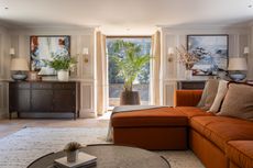 A living room with a burn orange sofa and layered lighting