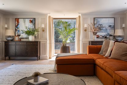 A living room with a burn orange sofa and layered lighting