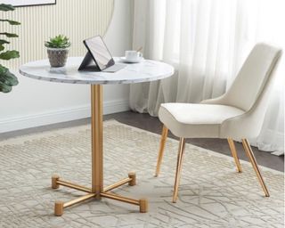 A stylish home office with a cream chair and round marble table