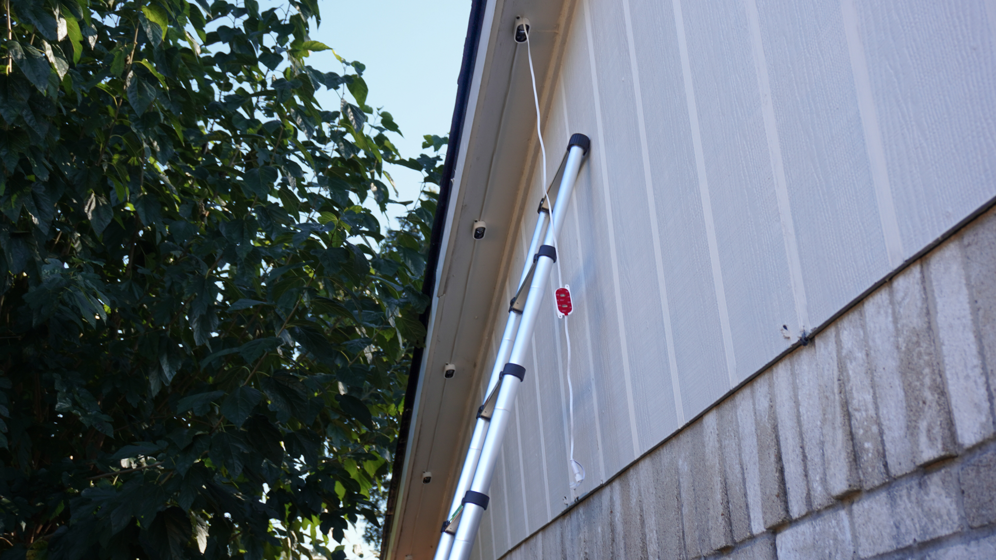 A ladder on the side of the house with Govee&#039;s Prism permanent outdoor lights being installed on the roof&#039;s soffit above