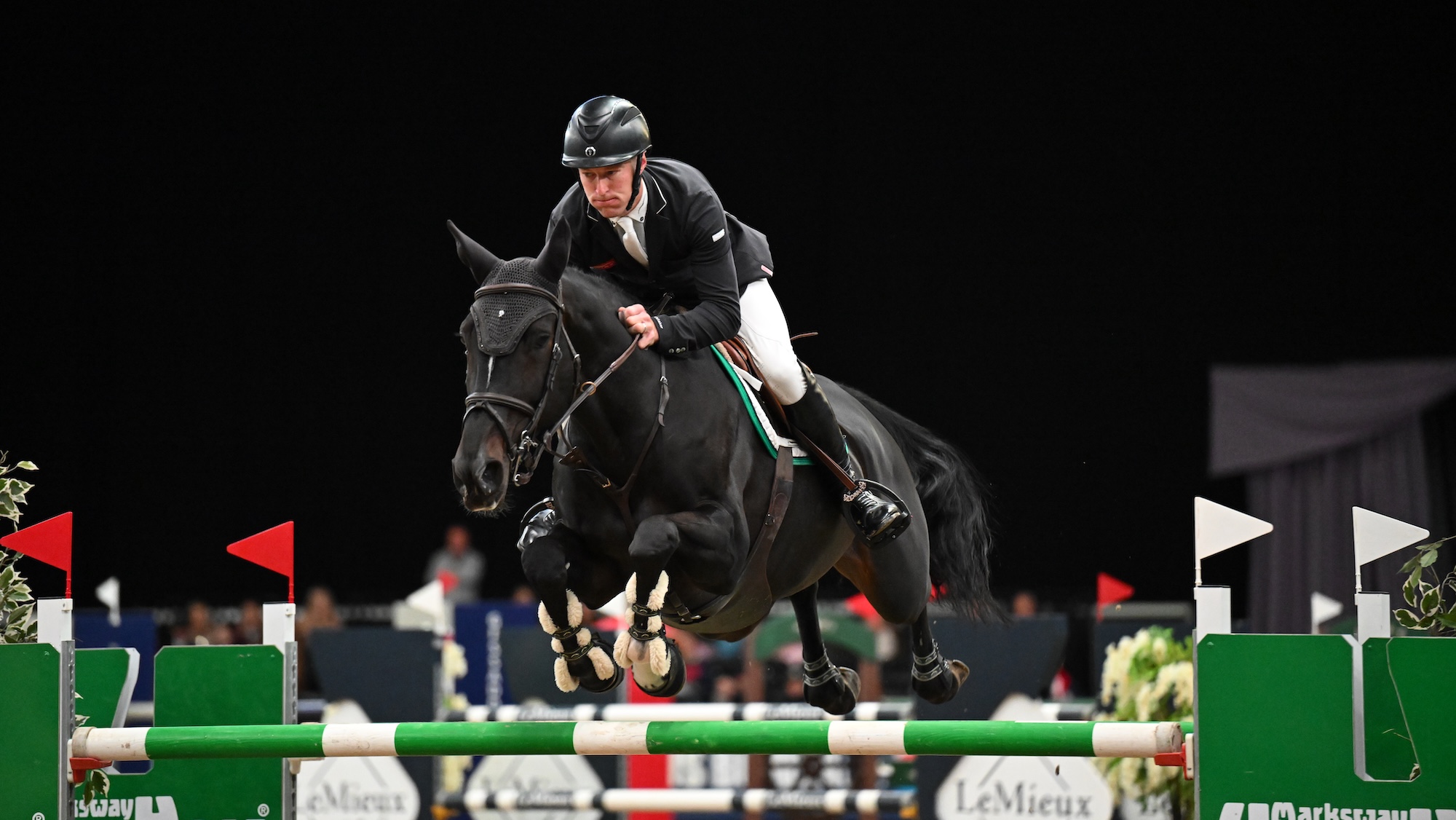 William Whitaker clears a fence at HOYS with a black mare