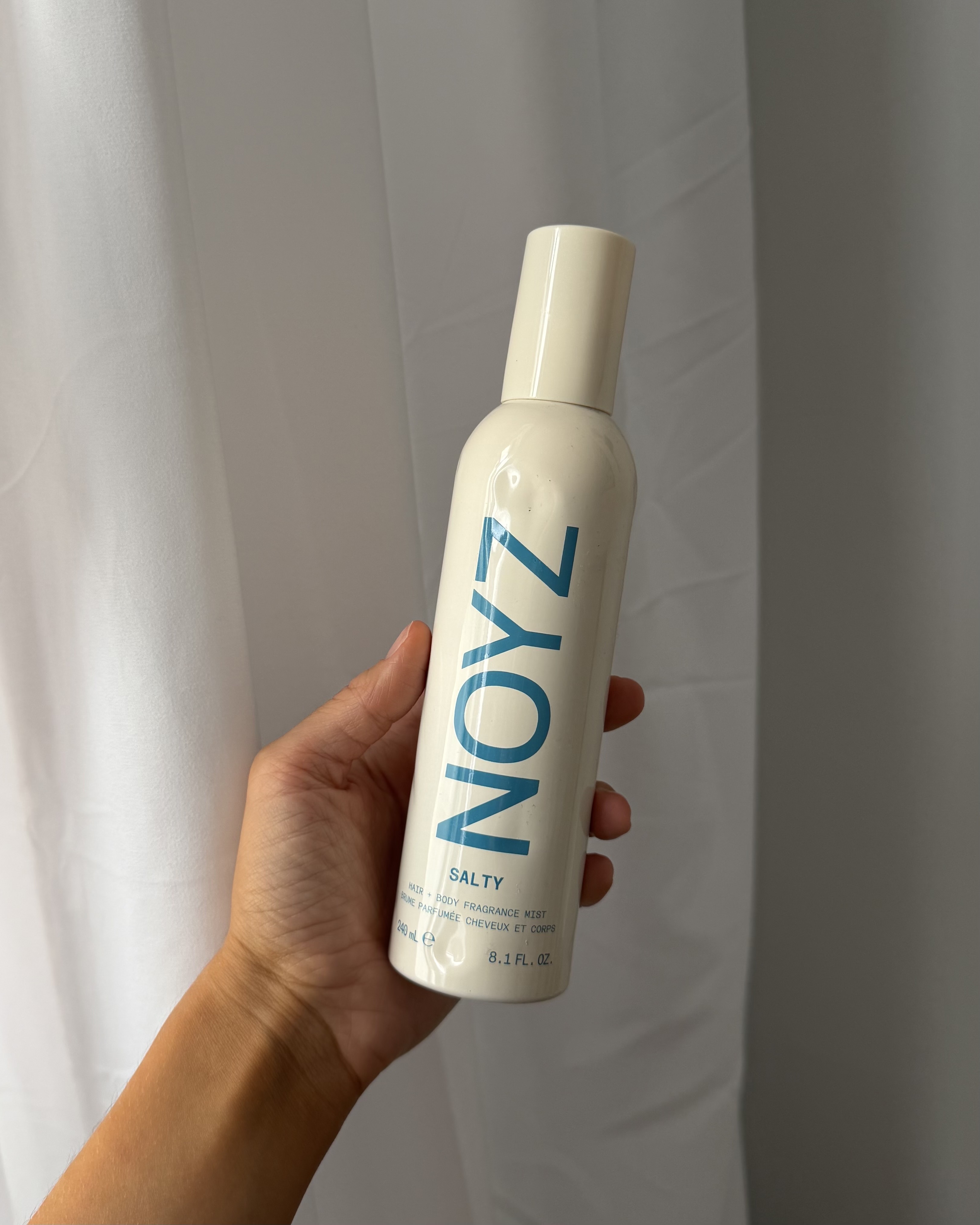 Who What Wear associate beauty editor Alyssa Brascia holding the Noyz Salty Hair and Body Fragrance.