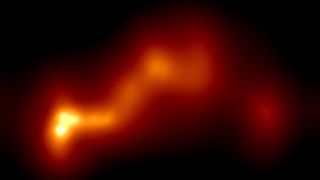 A glowing string of orange and yellow gas in the darkness of space, with a yellow end on the left showing a gas jet of a black hole