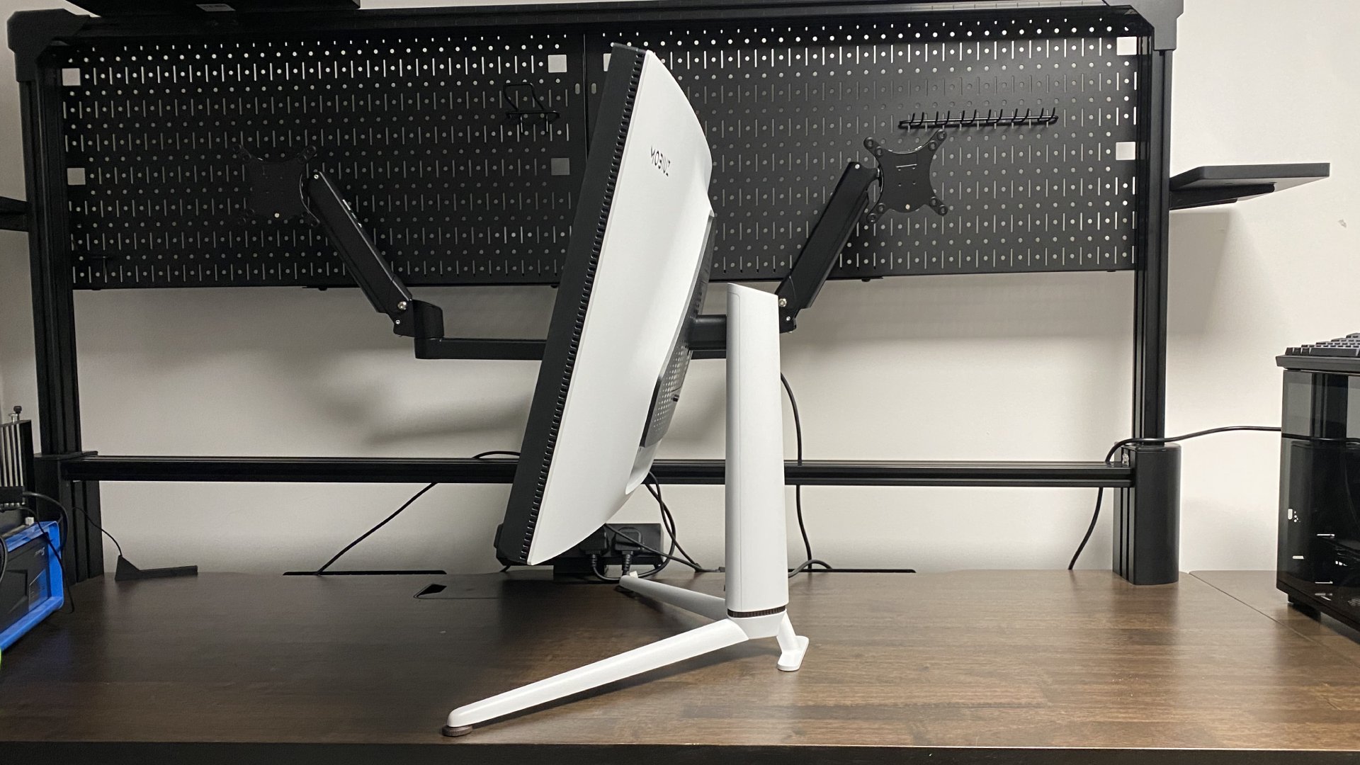 A photo of a BenQ MOBIUZ EX321UX gaming monitor on a desk, showing a view of the display from the side