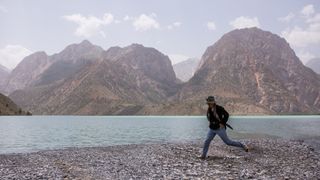A woman skips along a rocky lakeside, wearing a pair of Patagonia Women’s Chambeau Rock Pants.
