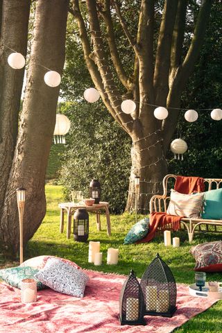 garden decor ideas: boho-inspired scene with hanging lights and outdoor rug