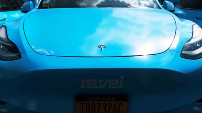 A blue Tesla featuring the branding of car app Revel
