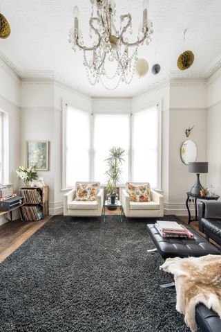 Living room with large grey rug and chandelier