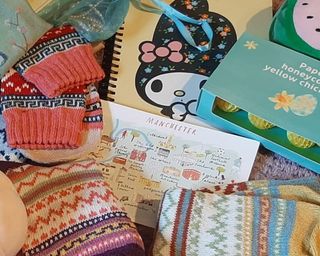 a close up photo of a pile of random decluttered items including notepads, graphics, knitwear and easter decor