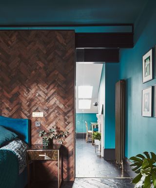 Moody bedroom featuring teal walls and ceiling and parquet dark wood wall panel