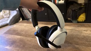 Sony Inzone H5 gaming headset being held over a wooden table