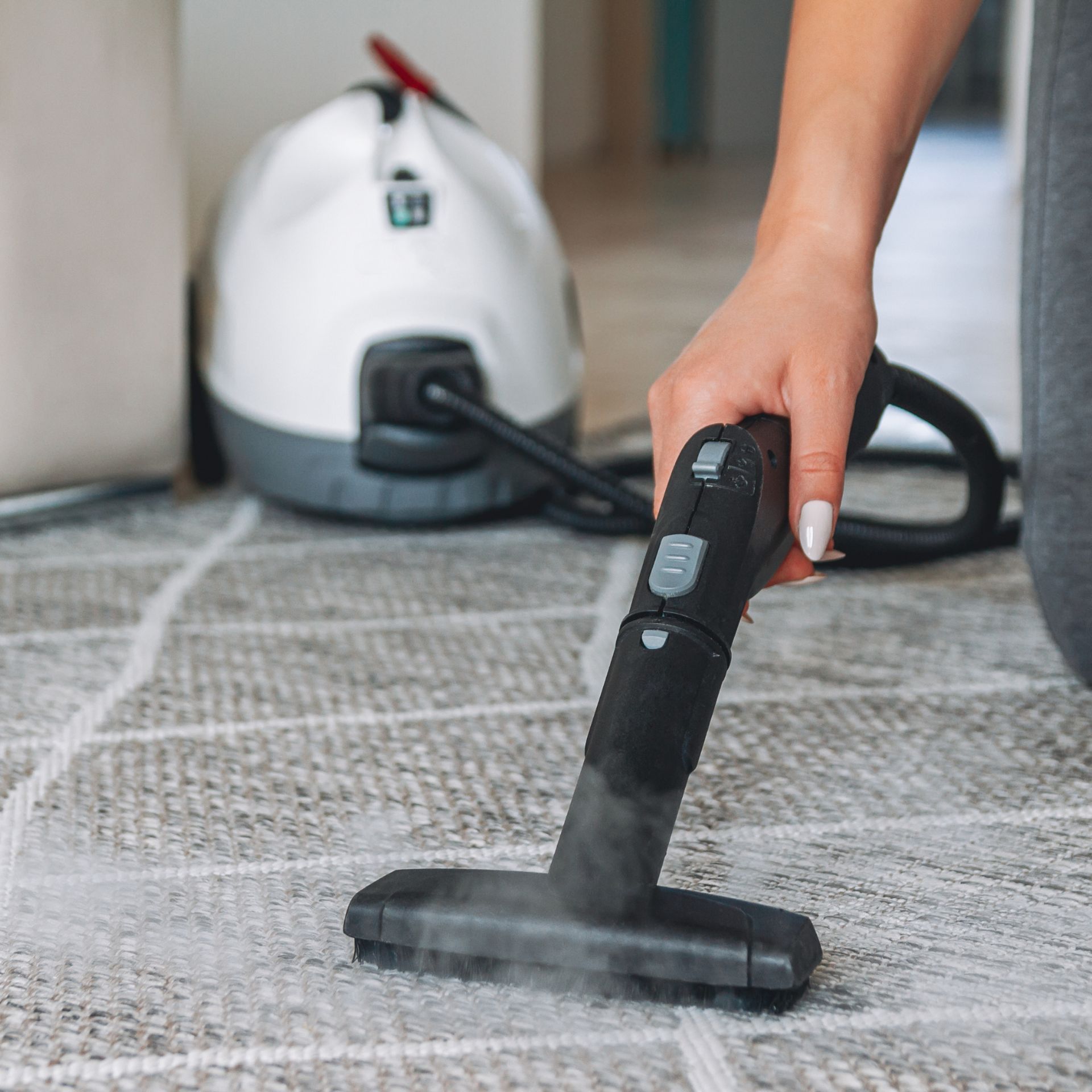 Woman cleaning carpet with steam cleaner