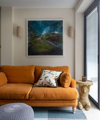 orange velvet sofa with monkey side table and artwork hung on wall above