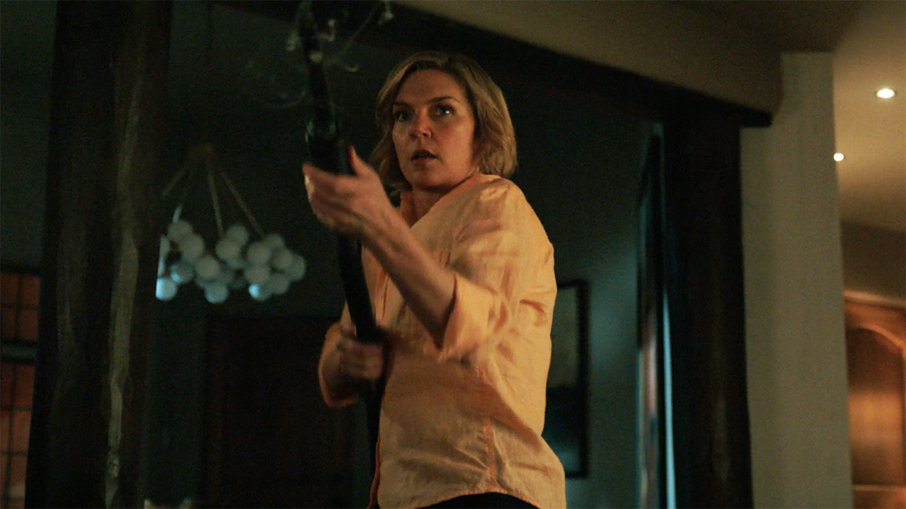 Carol brandishing a shotgun in a house at night in Pluribus episode 9