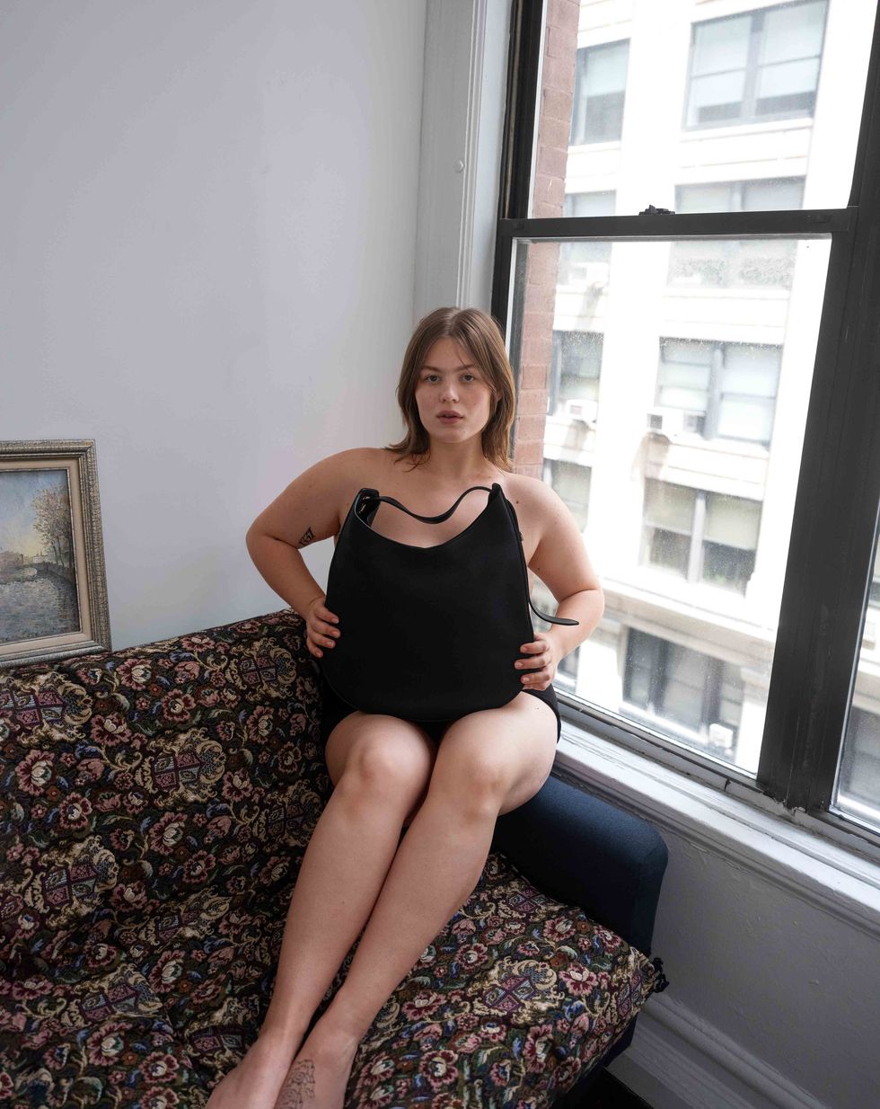 Model sitting of sofa with handbag on lap