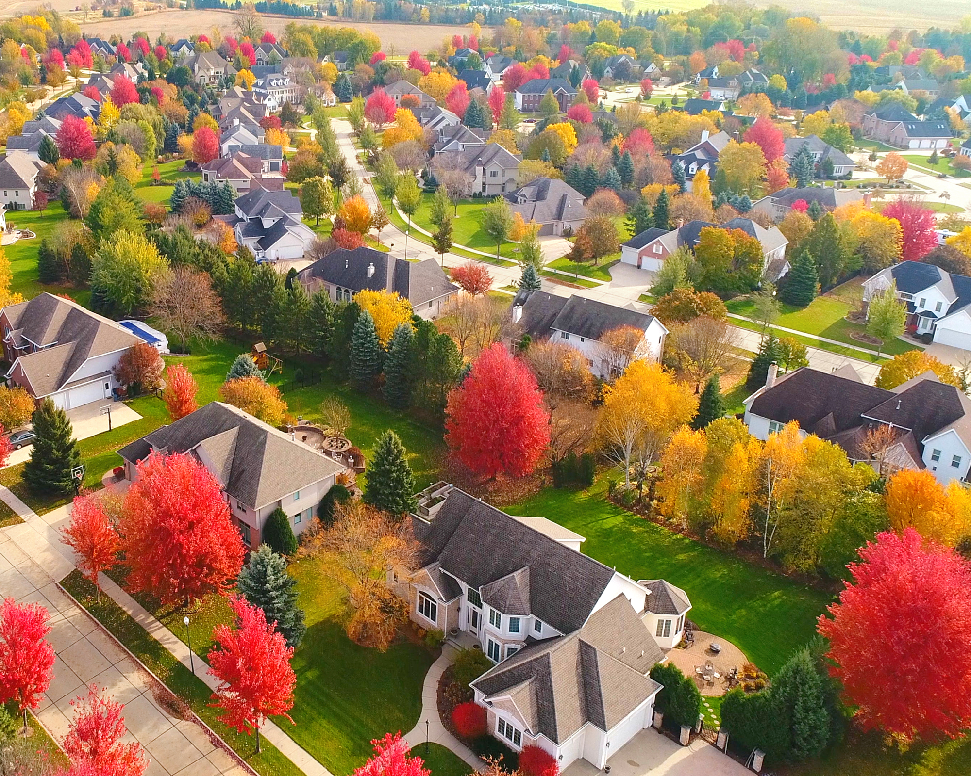 Breathtaking aerial view of idyllic neighborhoods richly colored with colorful Autumn trees.