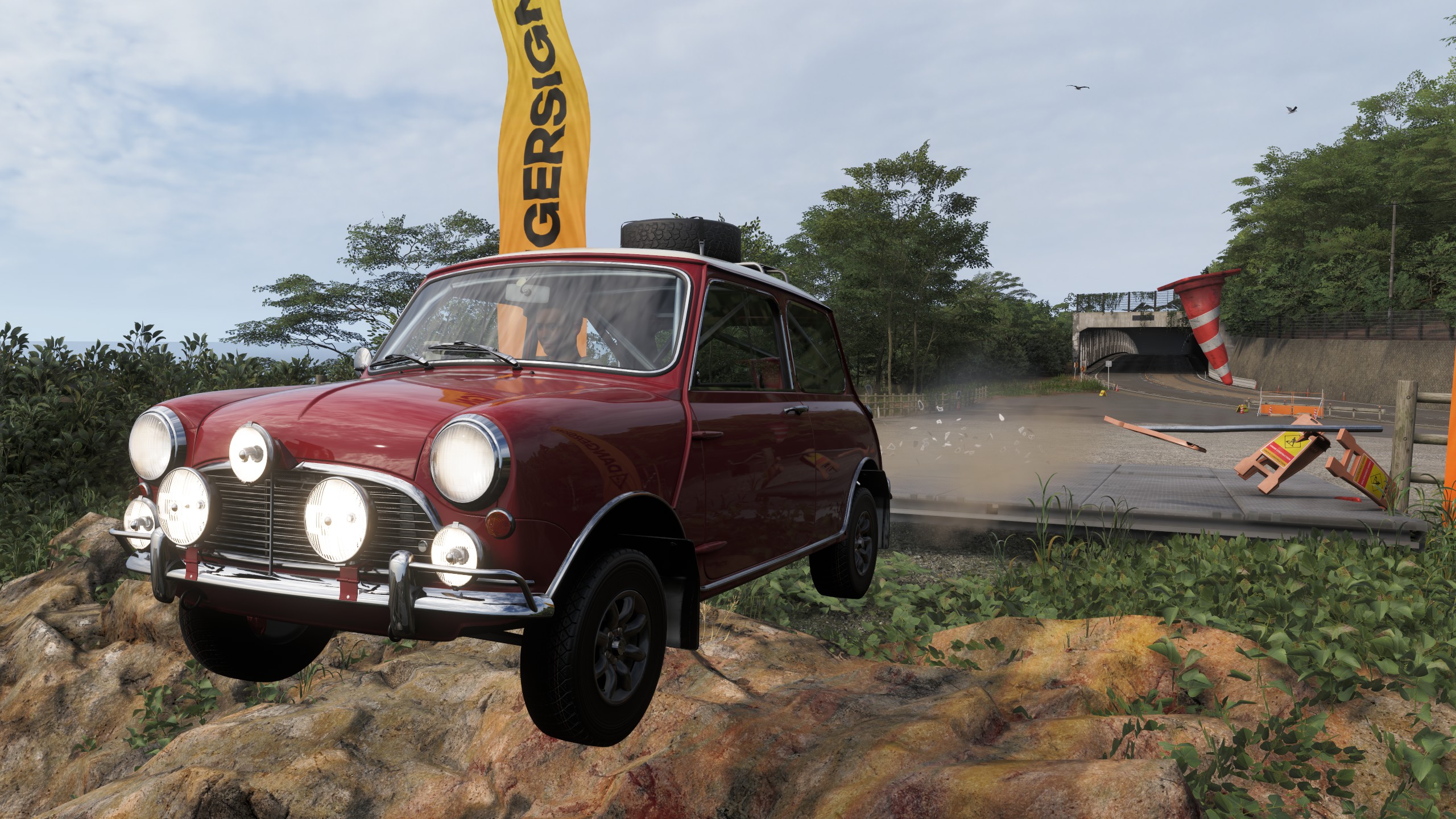 A Mini Cooper crashes through a danger sign jump.