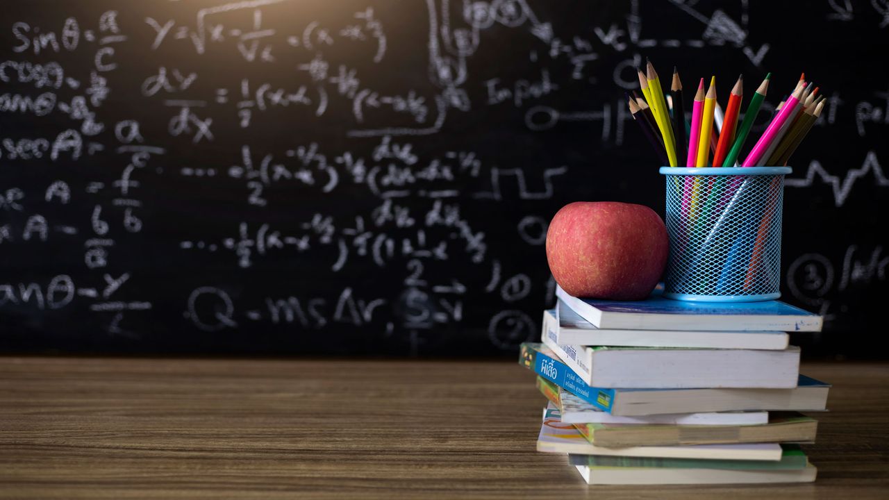 picture of books, pencils and an apple on a teacher&amp;#039;s desk