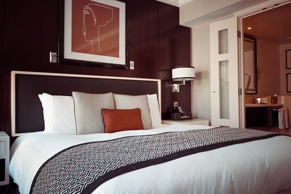 a modern bedroom with a deep red bedroom colour feature wall, white bedding and large print 