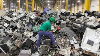 An employee reaches examines electronic waste awaiting to be dismantled as recyclable waste at the Electronic Recyclers International plant in Holliston, Massachusetts, USA.