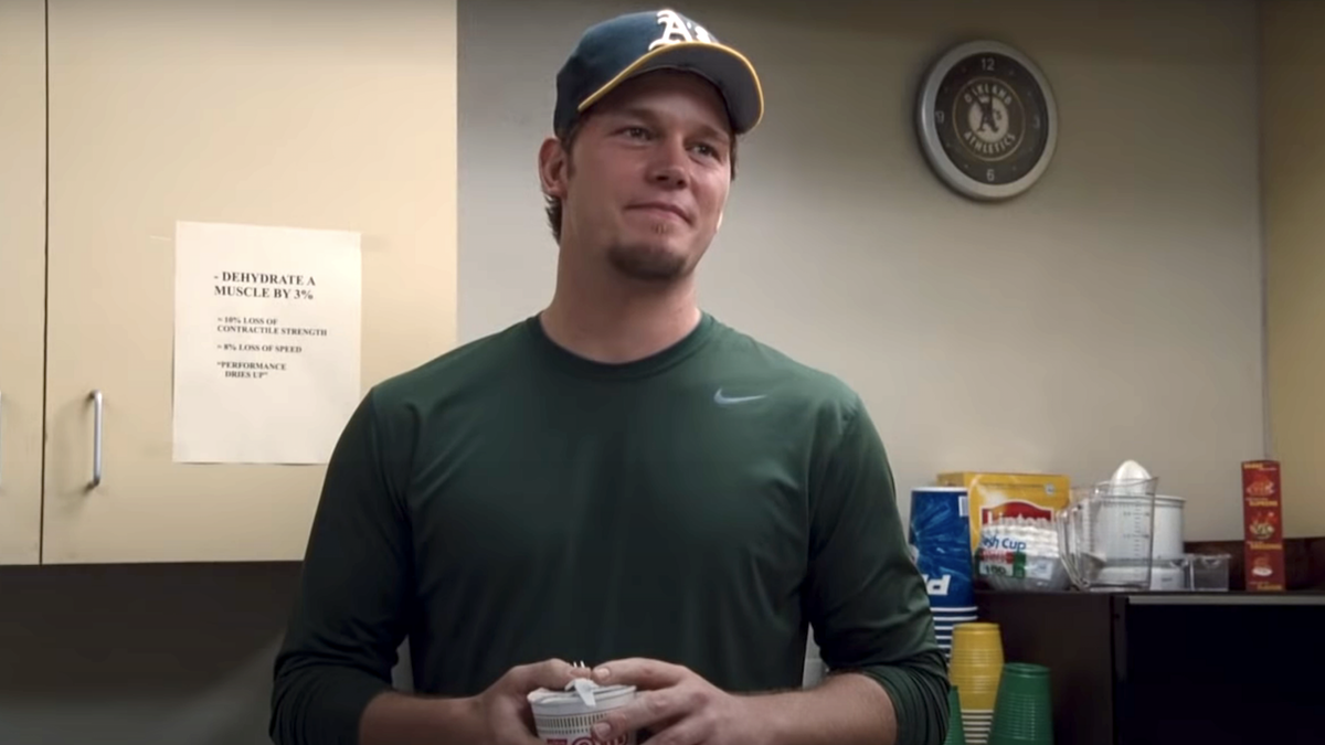 Chris Pratt, dressed in a green Nike shirt and wearing a green A&#039;s hat in Moneyball.