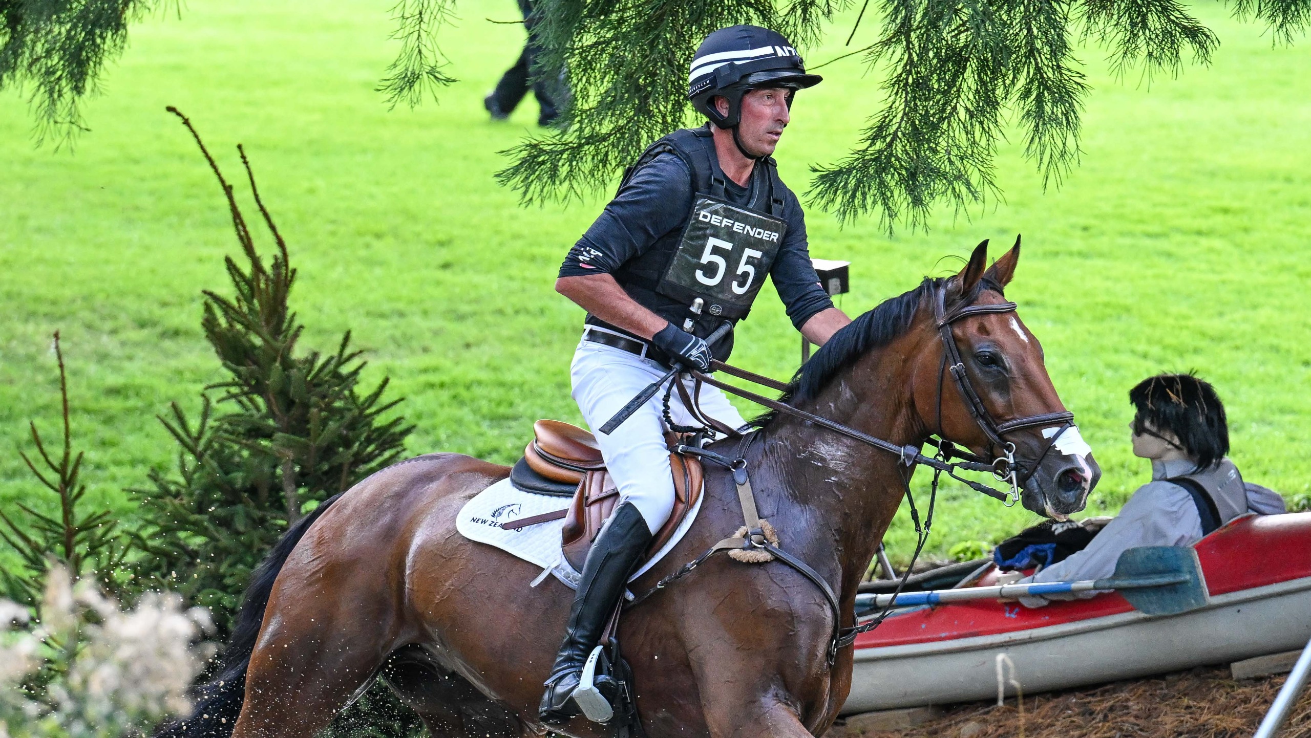 Tim Price, a rider in a black top and hat, rides bay horse Falco between fence at the 2026 Defender Burghley Horse Trials