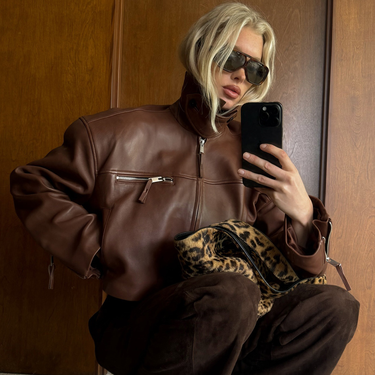 Elsa wears a brown leather jacket, leopard bag, and brown suede pants.