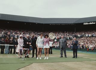 Queen Elizabeth II ( far left ) looks on as Virginia Wade of Great Britain holds aloft the Venus Rosewater Dish