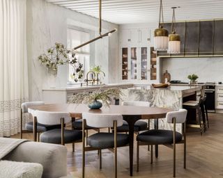 modern kitchen with white walls, marble island, white cabinets and wooden oval dining table with modern chairs