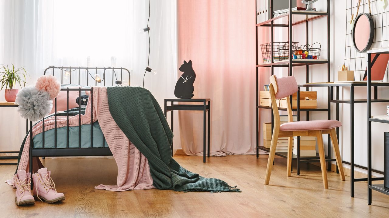 A pink bedroom with a bed, shelf, chair and desk