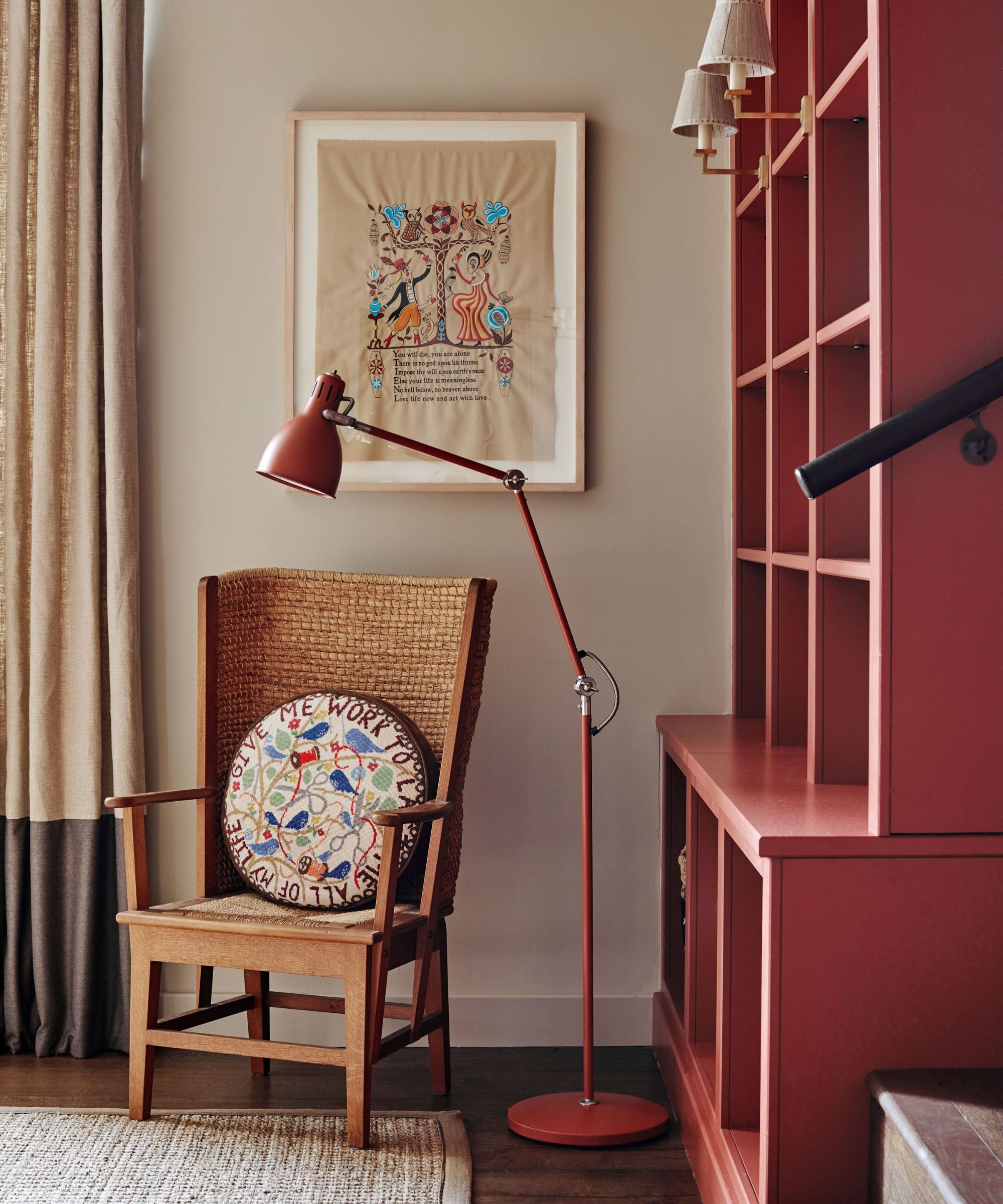 Living room with rattan chair, red floor lamp, red painted dresser and sconces
