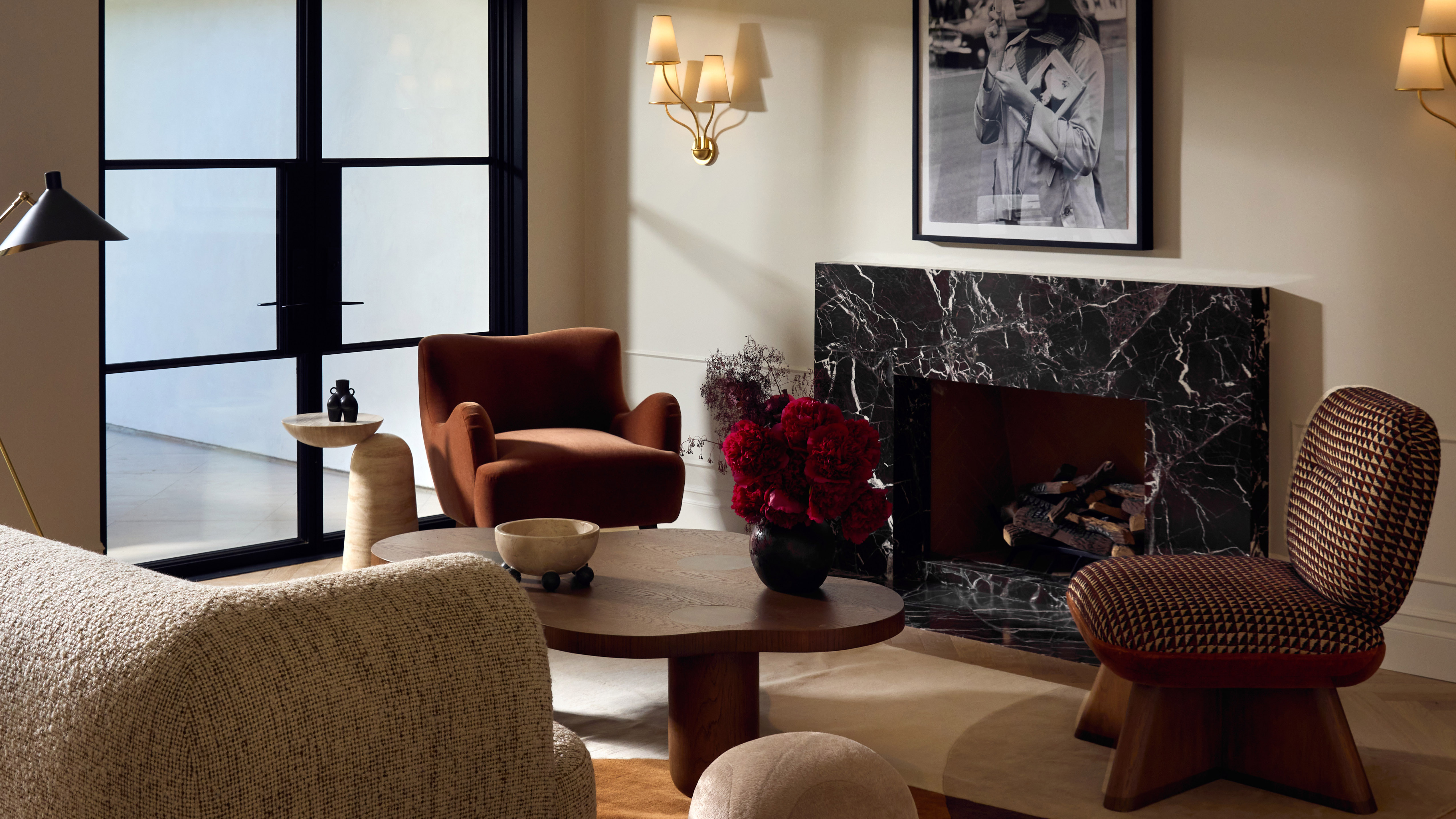 modern living room with rounded furniture, off-white walls and black marble fireplace