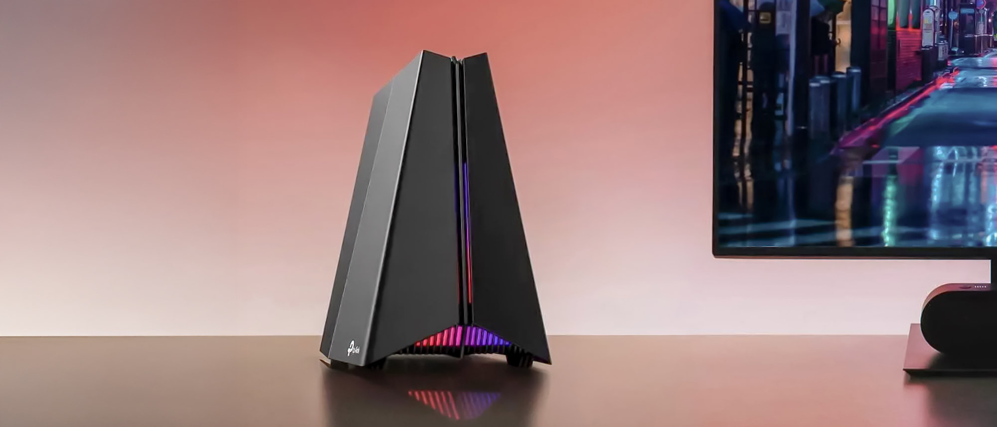A TP-Link Archer GE650 router on a desk next to a monitor