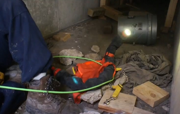 A robot snake uncoils to look around with its camera after being dropped off near a pretend disaster victim.