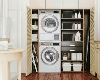shelving in cream fitted inbuilt cabinets with washsing machine and tumble dryer in a laundry room - smeg