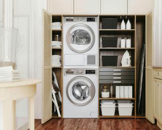 Shelving in cream fitted inbuilt cabinets with washing machine and tumble dryer in a laundry room