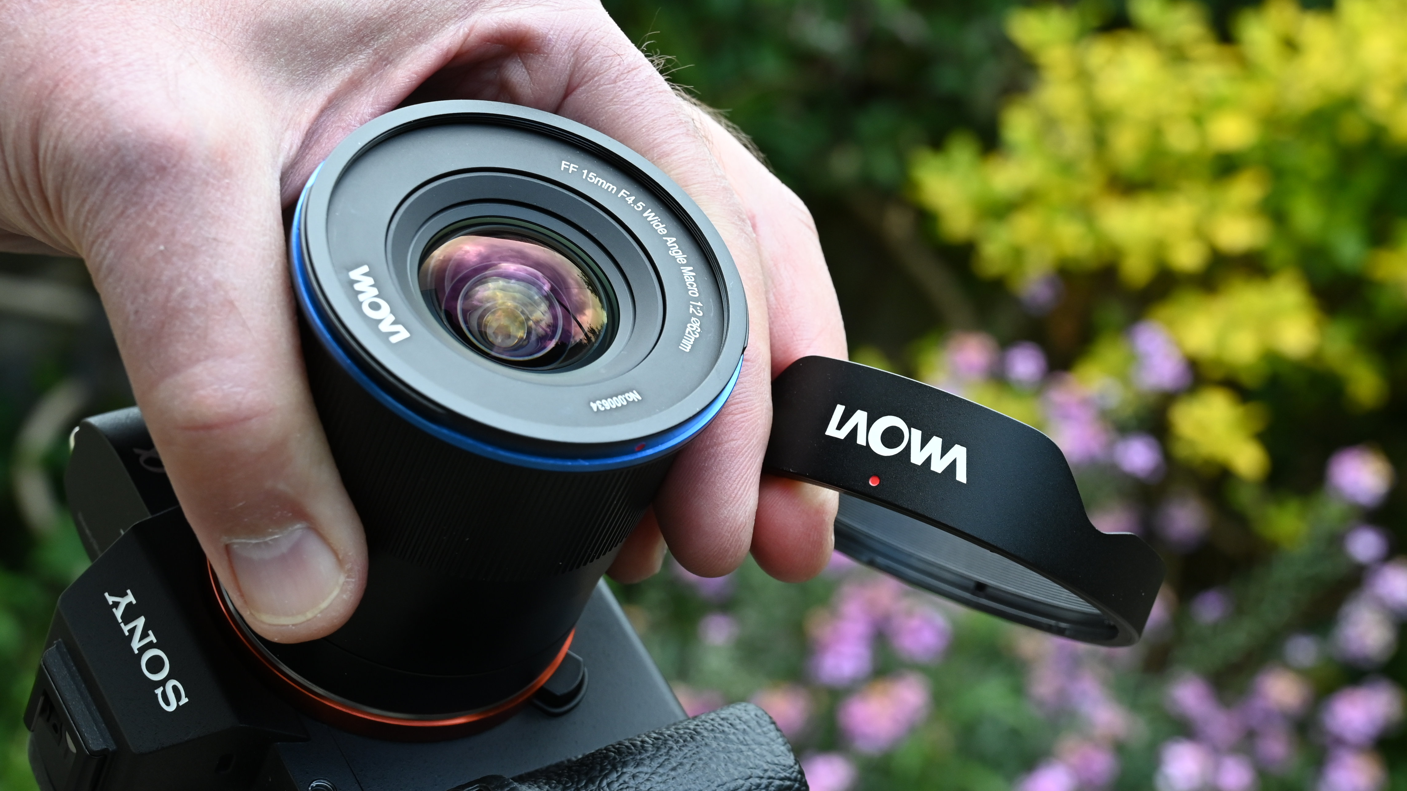Laowa 15mm f/4.5 0.5x Macro product shot with lens held in hand