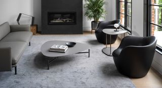 A grey rug with black furniture
