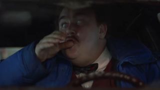 John Candy making a drinking motion while driving in Planes Trains and Automobiles.