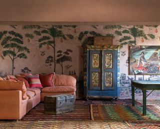 wall mural living room with terracotta pale orange sofa, vintage rugs, handprinted furniture