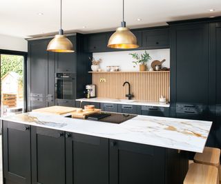 dark green kitchen with gold pendant lights, white and gold marble effect worktop and kitchen island