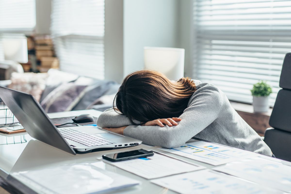 Visually stressed out woman with her head laying on a desk in front of her computer