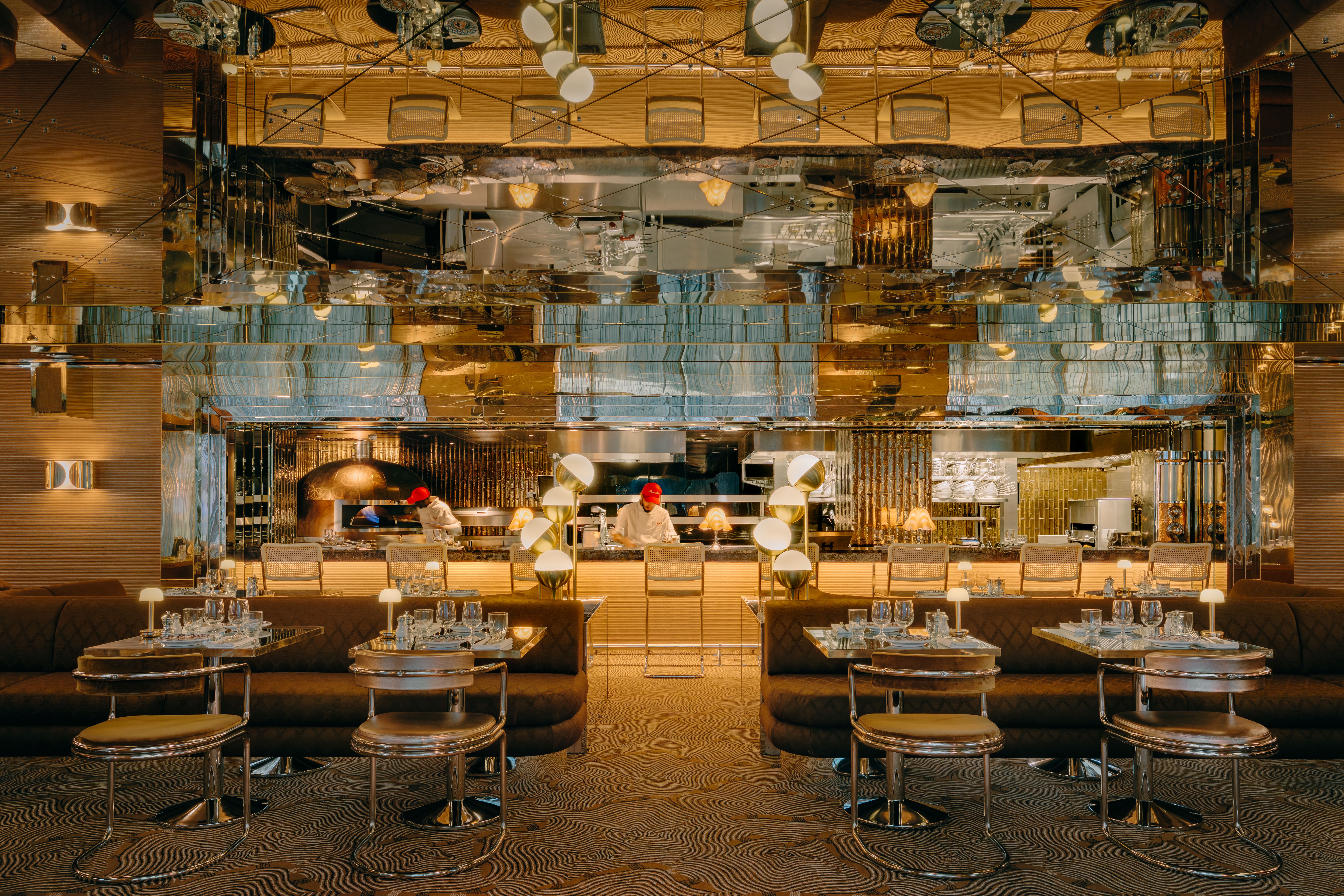 Interiors of Barbarella restaurant, with 1970s-inspired decor, reflective walls, and lots of contrasting textures and motifs, along with palm plants.