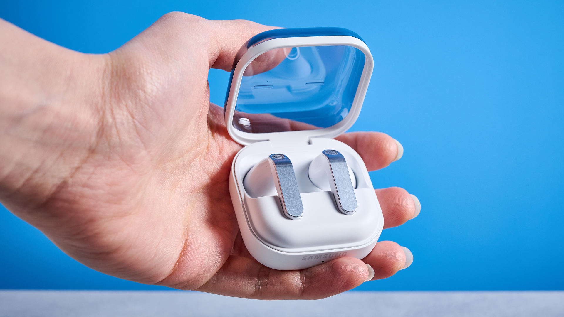 the samsung galaxy buds 4 photographed against the blue tom's guide background showing charging case and buds