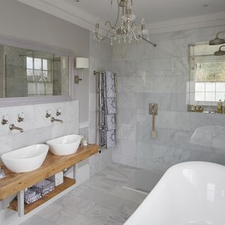 bathroom with chandelier and white bathtub and two basin