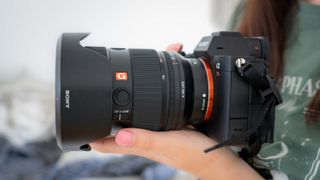Sony FE 24-70mm f/2.8 GM II lens held in a woman's hands