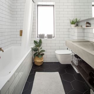 bathroom with white wall tiles and commode with bathtub
