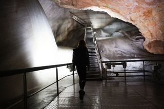 Image shows Anna walking through the Dobšinská Ice Cave while on a gravel bikepacking trip around Central Europe.