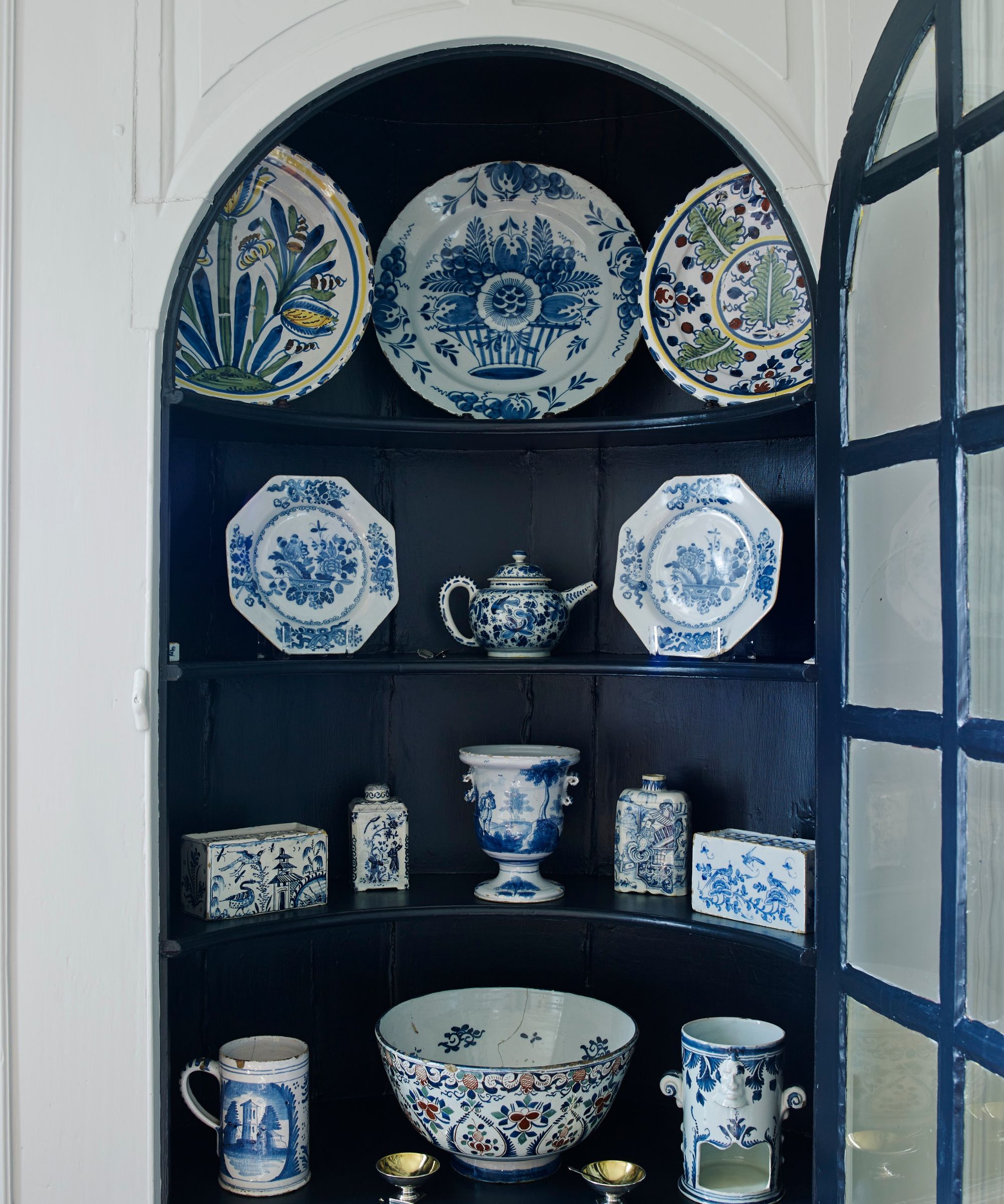Navy domed cabinet filled with blue and white vintage dishware